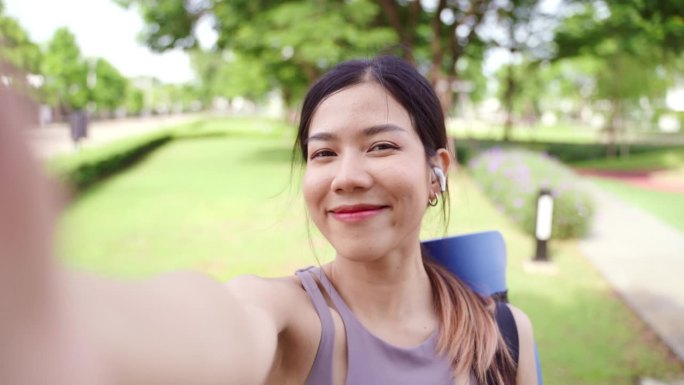 一名亚洲女性在公园做完瑜伽和运动后使用智能手机
