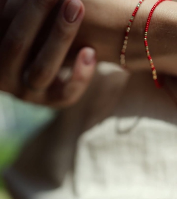 戴在女人手腕上的一种用红线做成的手镯，象征着莫尔斯电码的文本。胸饰女人手上的胸饰垂直特写视频