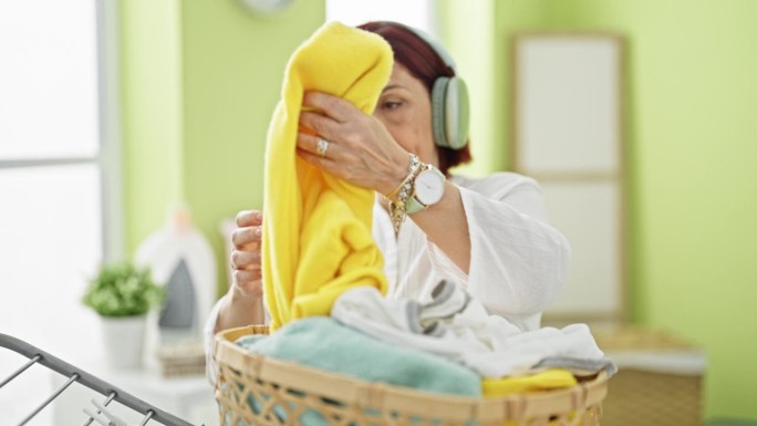 一位中年妇女在洗衣房边听音乐边把衣服挂在晾衣绳上
