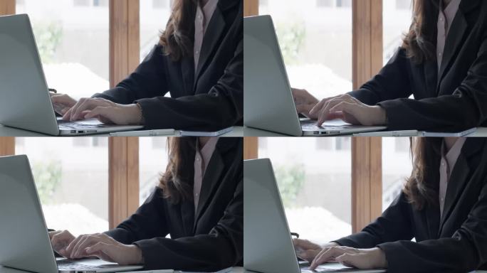 穿着黑色西装，面面相觑的年轻商人，双手在笔记本电脑上打字。