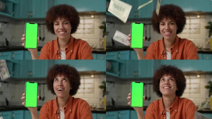 美元落在女性手中的绿屏手机。一名黑人女子正在展示彩色键智能手机，慢镜头里是钱掉下来的画面。