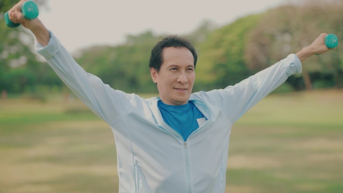 户外健身套路:亚洲成熟男子用哑铃进行健康运动，鼓励健康习惯