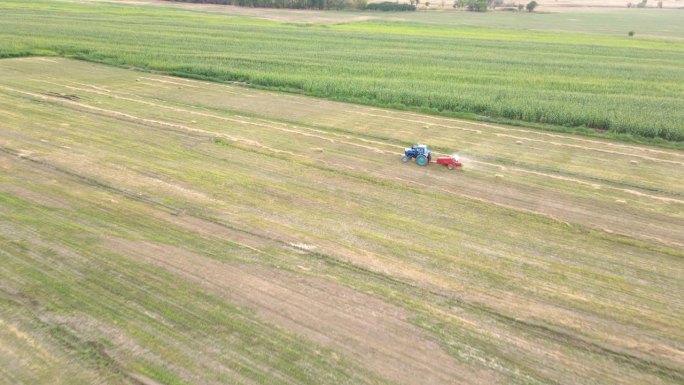 拖拉机打包机机在田野上收集干草