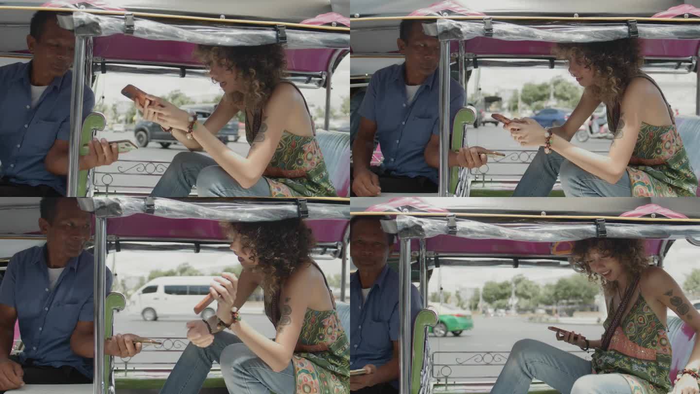 一名亚洲女游客在冒险骑完嘟嘟车后，用智能手机进行非接触式支付。