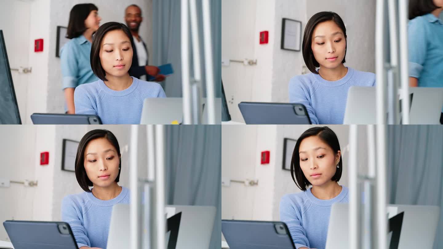 女电脑程序员坐在联合办公桌旁使用笔记本电脑