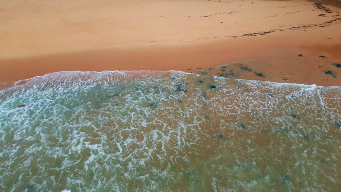 在阴暗的日子里，泡沫的海浪冲刷着沙滩。海浪翻滚的海滩