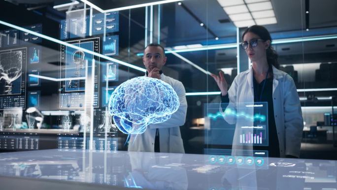 两位神经科学家在未来实验室中使用计算机驱动的人类大脑和神经系统动画全息图。多民族男女致力于脑肿瘤的解