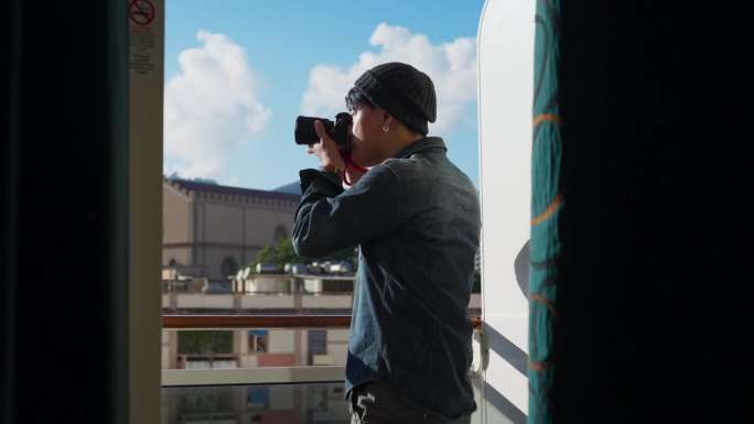 亚洲男摄影师旅行者穿着休闲的衣服在他的游轮阳台房间拍照，潮人在意大利用相机捕捉瞬间