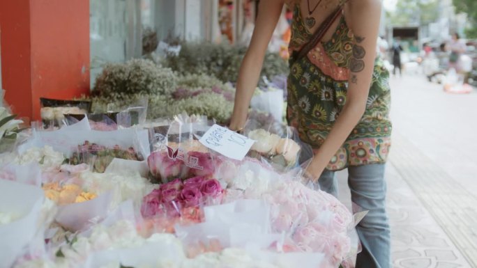 一位女游客在她的假期旅行中在鲜花市场的人行道上购物。