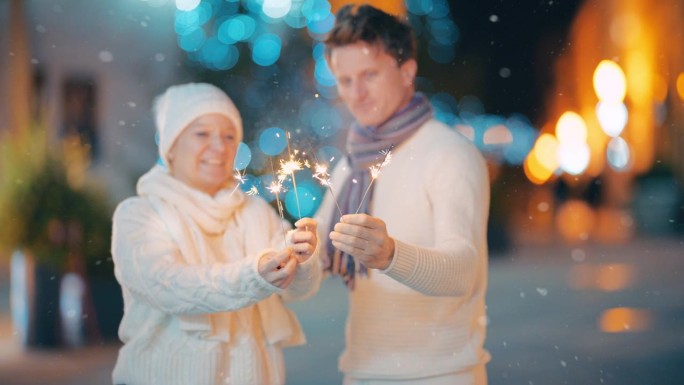 在卡科维奇一条充满活力的圣诞主题小巷里，雪花落在一对拿着烟花的夫妇身上