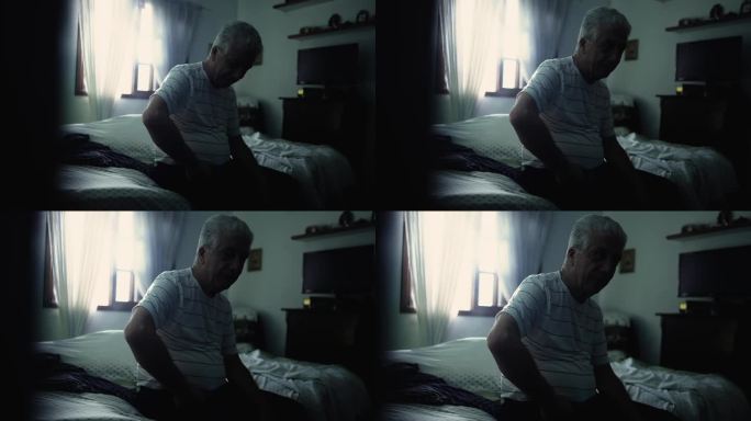 忧郁的老人坐在阴暗的卧室床边。一个孤独的老人独自挣扎的戏剧性的黑暗和阴郁的场景