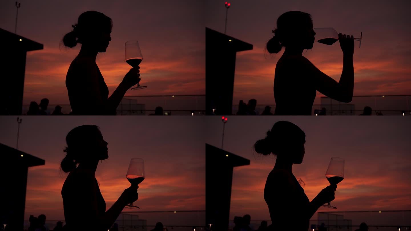 太阳落山时屋顶餐厅里喝红酒的女人的剪影。
