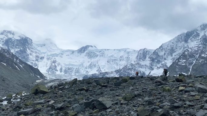 两个背着大背包的登山者正在岩石上行走。Belukha攀升。令人惊叹的阿克姆长城，阿尔泰，俄罗斯