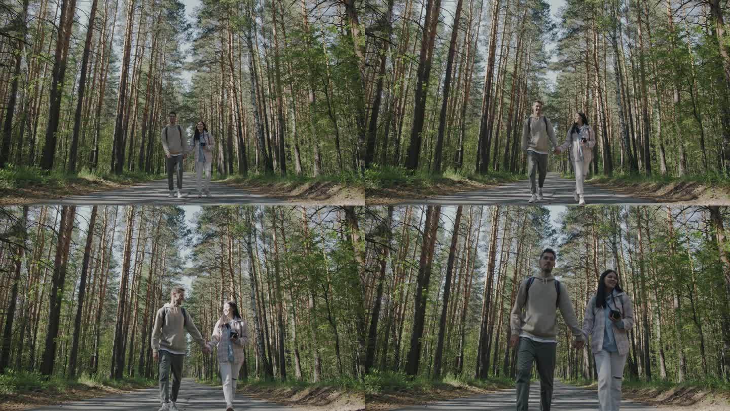 女孩和男孩幸福的年轻夫妇走在森林里在美丽的夏日牵着手聊天