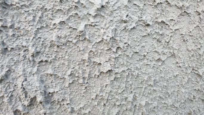 墙上的灰泥。灰泥墙，凹凸不平，硬梆梆的。建筑立面，灰色粗糙的灰泥。