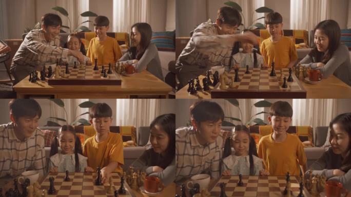 一个幸福的韩国家庭在家里的客厅里共度时光。聪明的小男孩试图在一场国际象棋比赛中战胜支持他的爸爸、妈妈