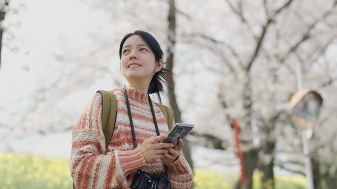 亚洲年轻女子独自坐着，看着草地，感觉放松和清爽的假期