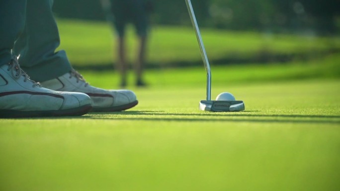 活跃的职业高尔夫球手打高尔夫球与俱乐部在推杆绿色高尔夫球场。
