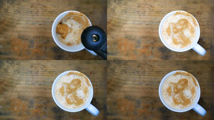 一个热气腾腾的咖啡杯，俯视图:一个人把沸水倒在一杯奶油咖啡上。用勺子搅拌咖啡。桌上有一杯咖啡。工作台