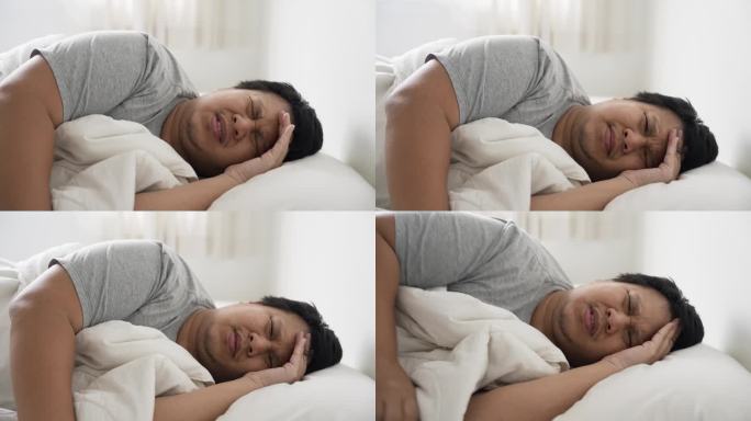 生病的亚洲人躺在床上头痛
