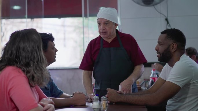 老年服务员在当地餐厅与顾客互动，接单并参与顾客对话