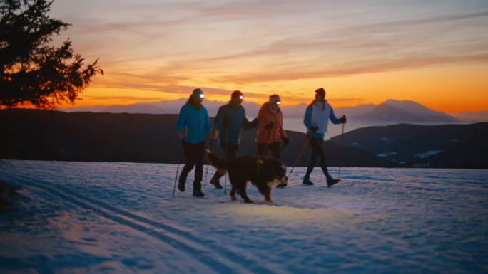 傍晚，一家几代人带着他们的狗在雪地里徒步旅行