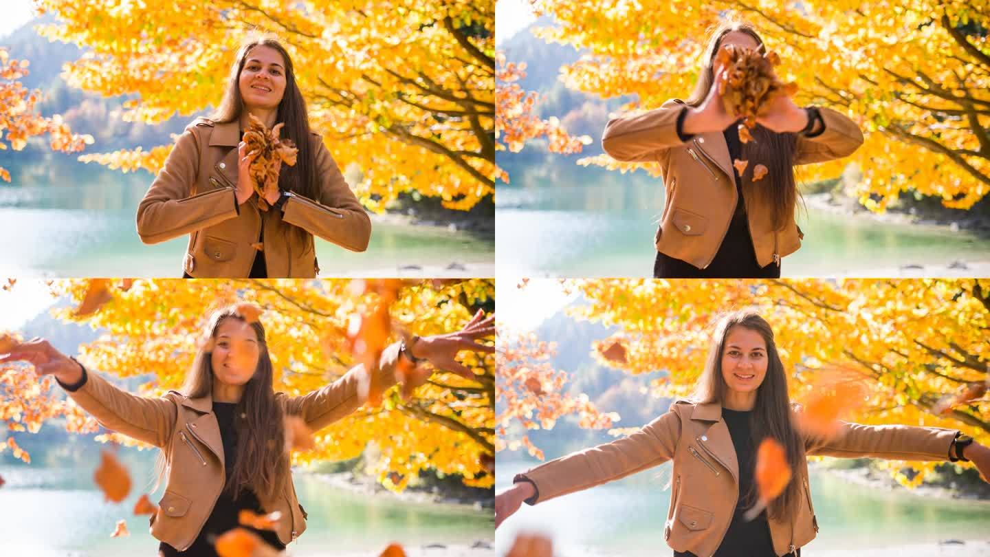 女人微笑着，向镜头扔着五颜六色的树叶