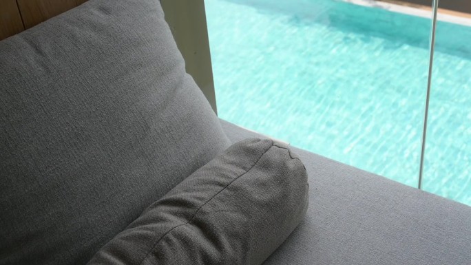 灰色的枕头放在床上，游泳池的景色和慢动作的水波