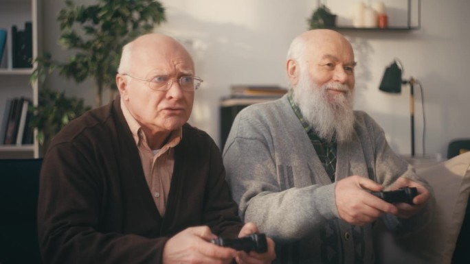 两个快乐的老人玩电子游戏，休闲活动，老年人的生活方式