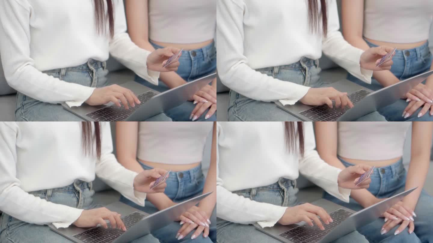 近景:两位亚洲女性坐在家里的沙发上，通过笔记本电脑使用网上购物信用卡。在线成功购买销售。