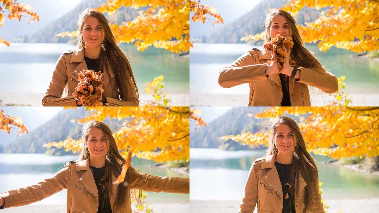 女人微笑着向镜头扔着五彩缤纷的秋叶