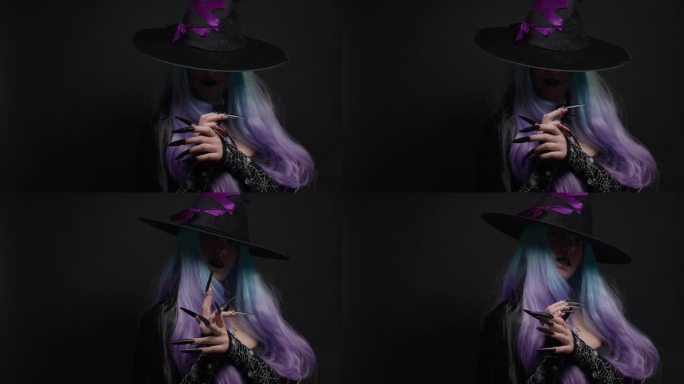 万圣节巫婆穿着黑色的衣服，披风，戴着紫色丝带的黑帽子，蓝色和紫色的头发和长长的黑色指甲。