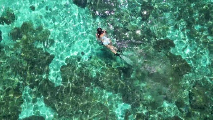 女性在海洋珊瑚礁周围浮潜的鸟瞰图