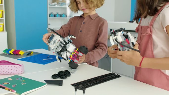 学龄前男孩和女孩在爱好俱乐部建造电动玩具机器人