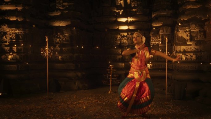 在一座古老的寺庙外，一位穿着传统服装的活跃的印度女舞者的慢动作肖像。她展示了Bharatanatya