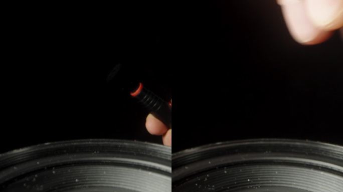 把相机镜头的前镜头放在黑色的背景上，我用刷子把它从灰尘上擦干净。垂直视频。