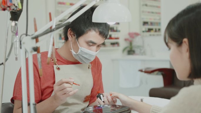 亚洲男性美容技师在美甲沙龙提供美甲服务