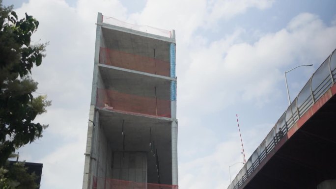 位于布鲁克林的高架公路旁，新建造的混凝土建筑又高又窄，边缘参差不齐，周围包裹着橙色防护网