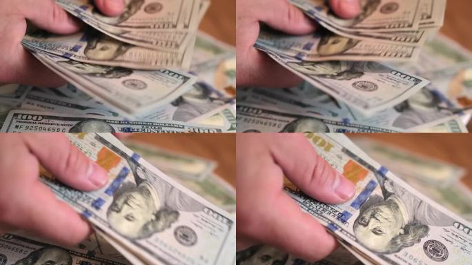 男性双手迅速数出现金100元，并伸出一部分钱来分收入