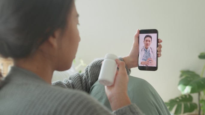 近距离的亚洲年轻女孩患者通过手机视频通话咨询医生药物剂量说明在医疗app上在家远程医疗在线服务。居家