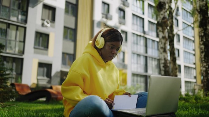非裔美国女孩在线学习，看笔记本电脑显示，使用无线耳机