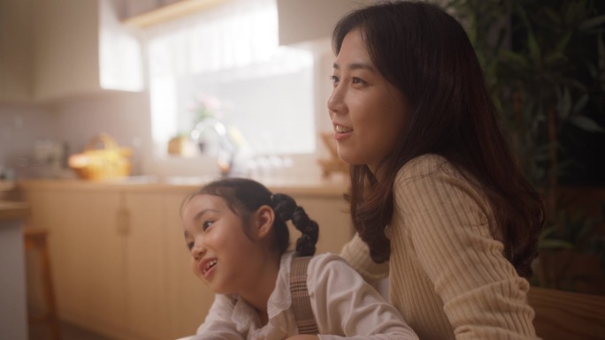 一位韩国母亲和她的小女儿在家里参与对话的肖像。在一个快乐的周末早晨，家人聚在一起，相互联系，交谈，讨