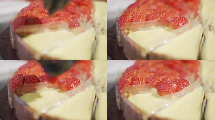 一个戴着黑色手套的厨师的手在草莓奶酪派上把草莓片围成一个圈。装饰蛋糕。制作草莓芝士派甜点的过程