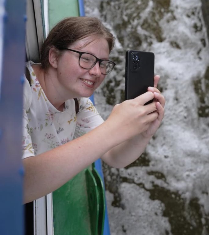游客在游船上用智能手机拍下水闸的照片。