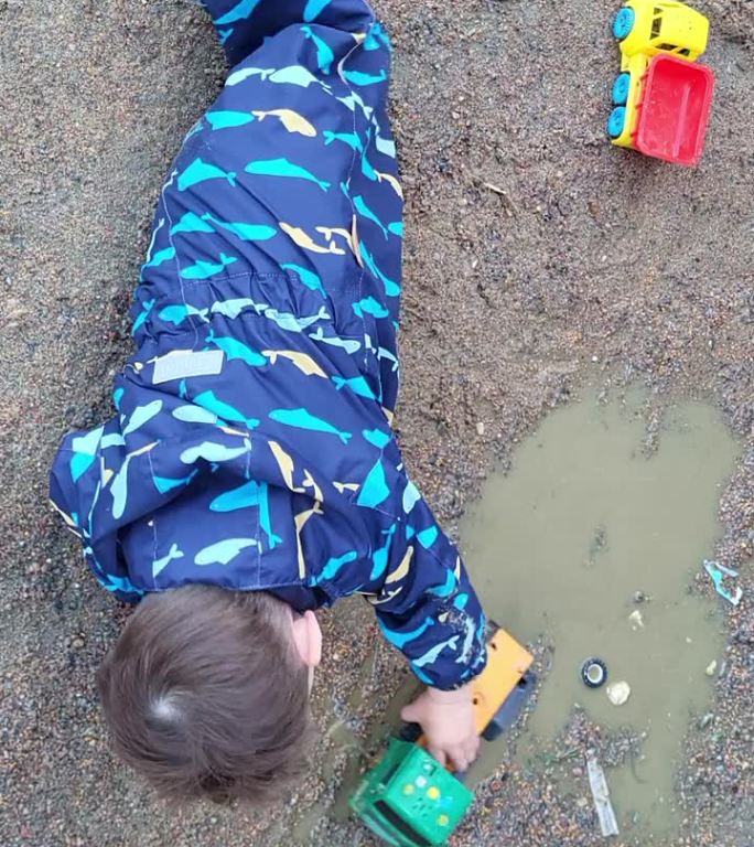 宝宝带着好奇心在水坑里摸索，用手摸着水和泥