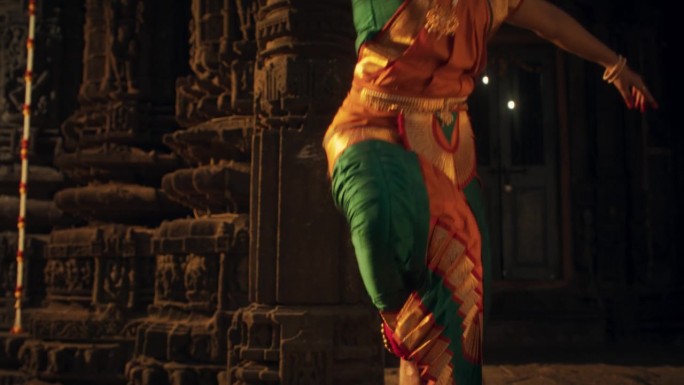 精力充沛的印度妇女在跳Bharatanatyam时，展示了她的腿在传统服装中的优雅运动。女舞者在古庙