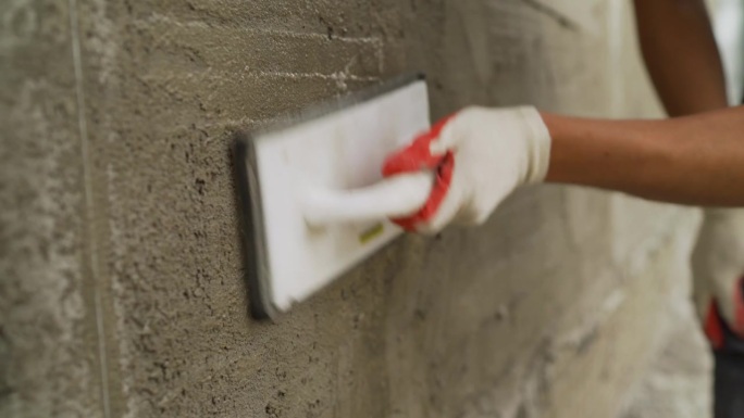 用海绵清洗腻子，以便找平。用海绵清洗腻子。用腻子修补建筑物外墙。手工工人在墙体结构上抹水泥的特写。