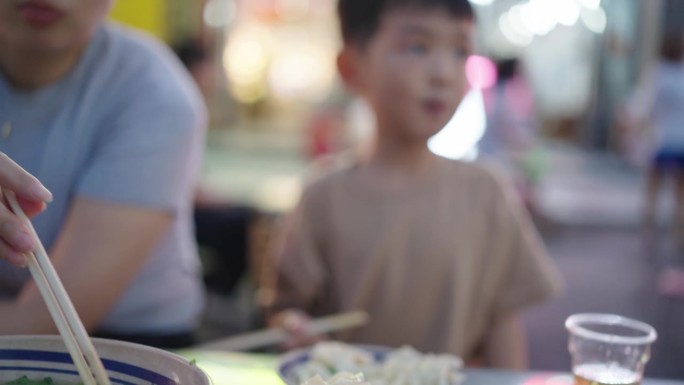 母亲和儿子在街头美食节上吃饭