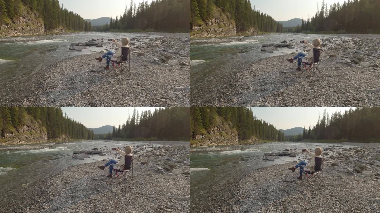 女子在石质河岸上放松，用智能手机拍照