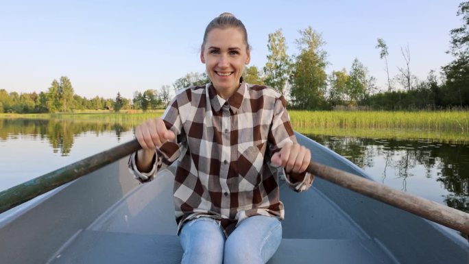 在一个阳光明媚的夏夜，快乐的女子在拉脱维亚的湖面上划船